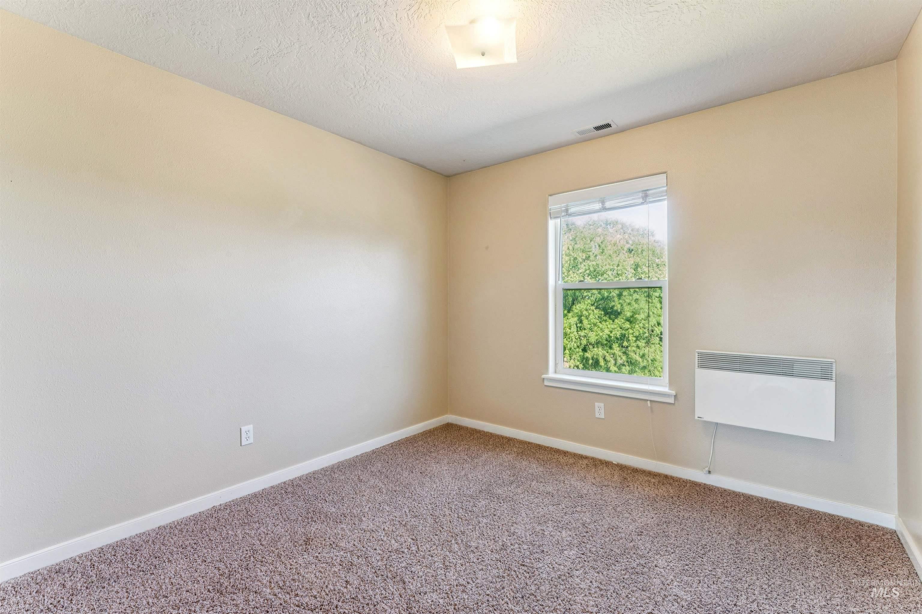 Carpeted empty room featuring baseboards and a textured ceiling