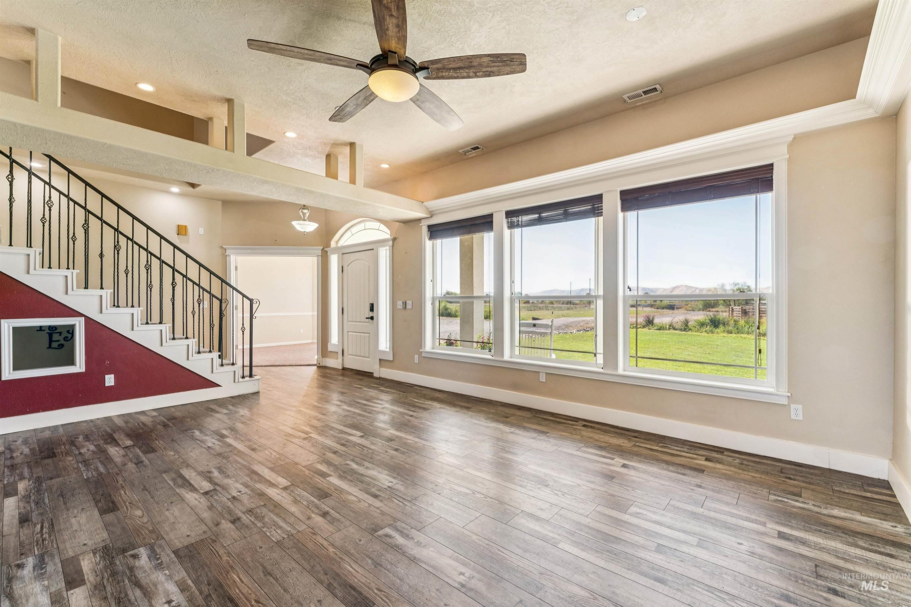 Unfurnished living room featuring wood finished floors, stairway, a ceiling fan, recessed lighting, and a textured ceiling