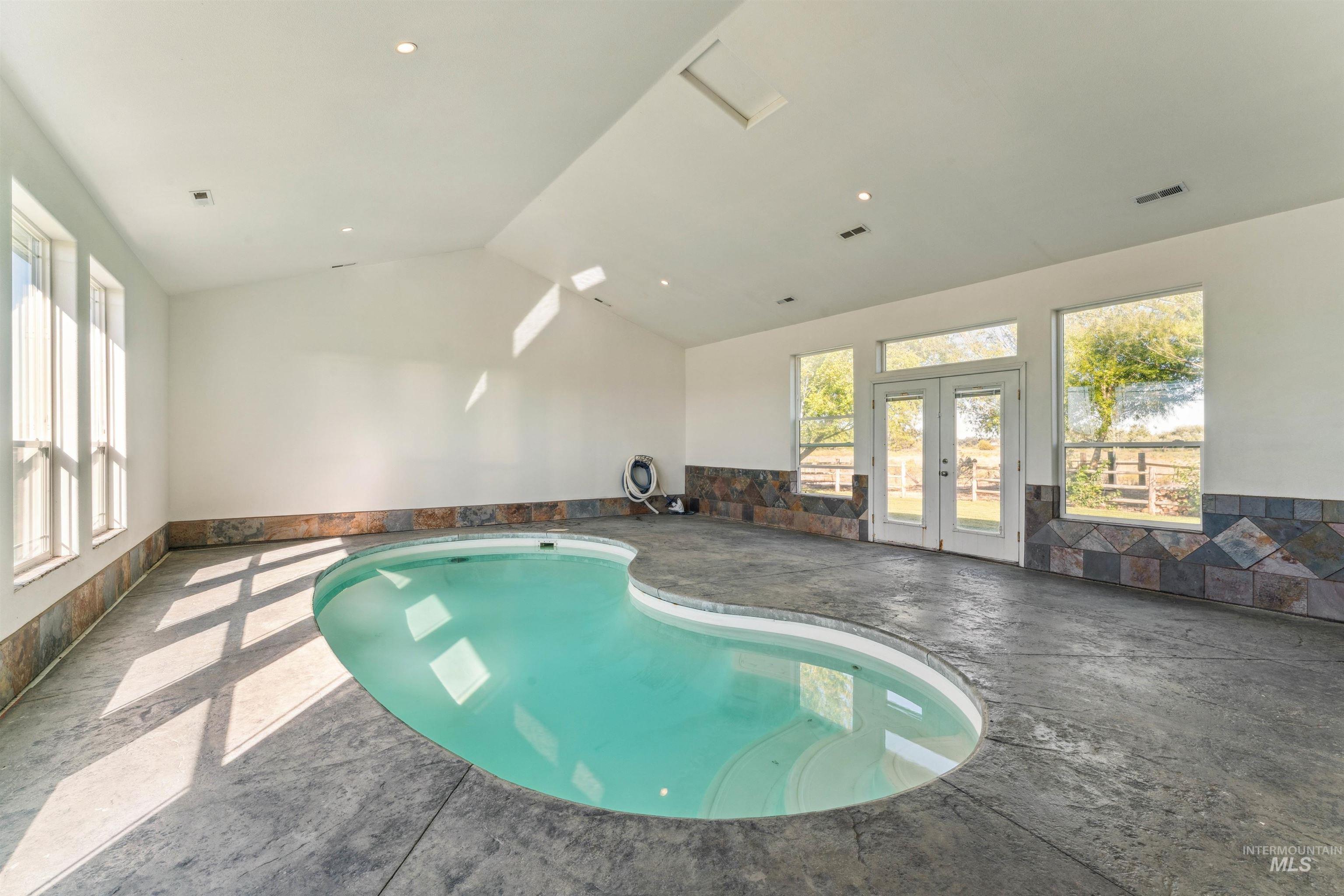 Indoor pool featuring french doors and a sunroom