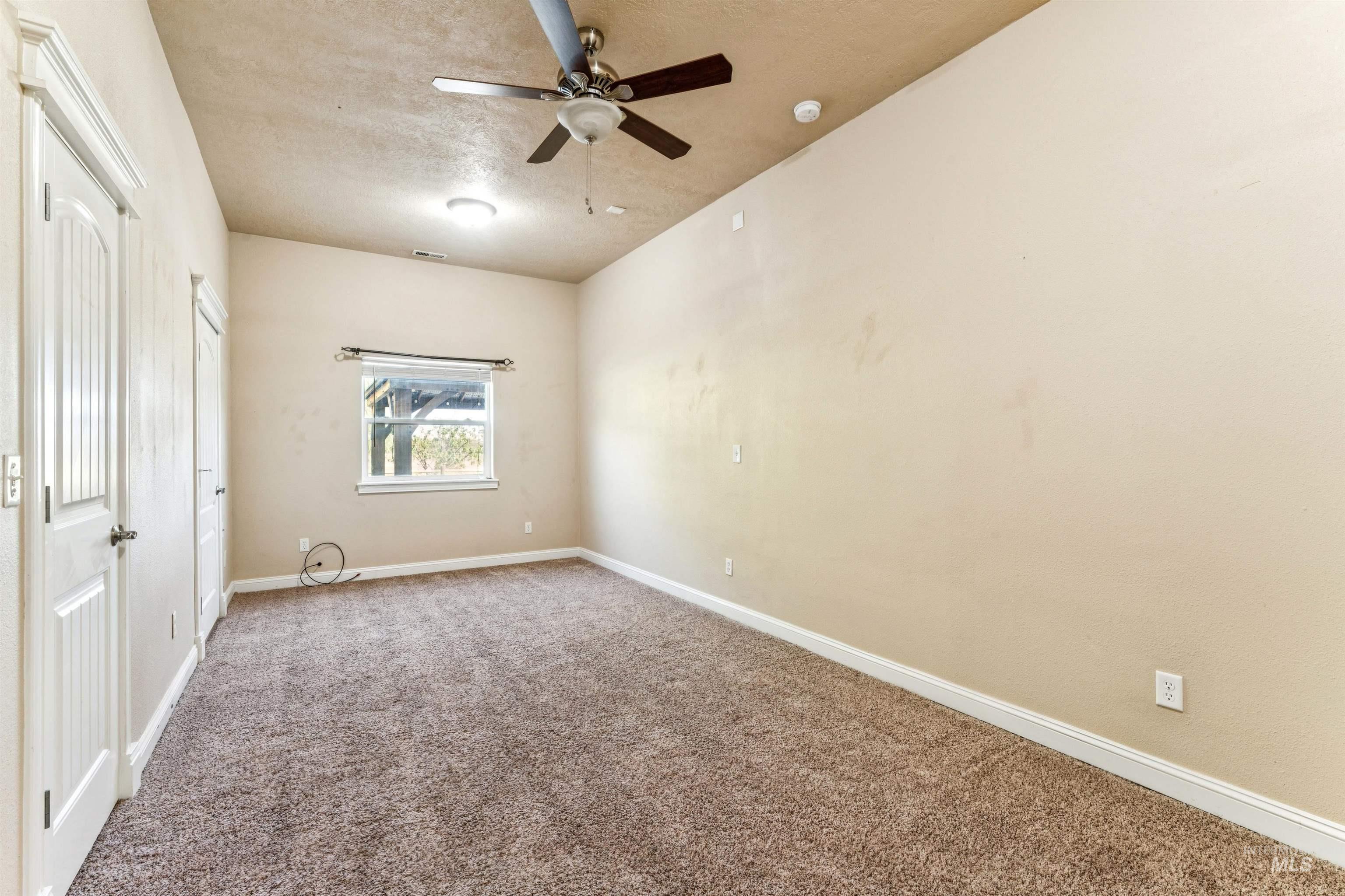 Unfurnished bedroom featuring carpet flooring, a closet, a textured ceiling, and a ceiling fan