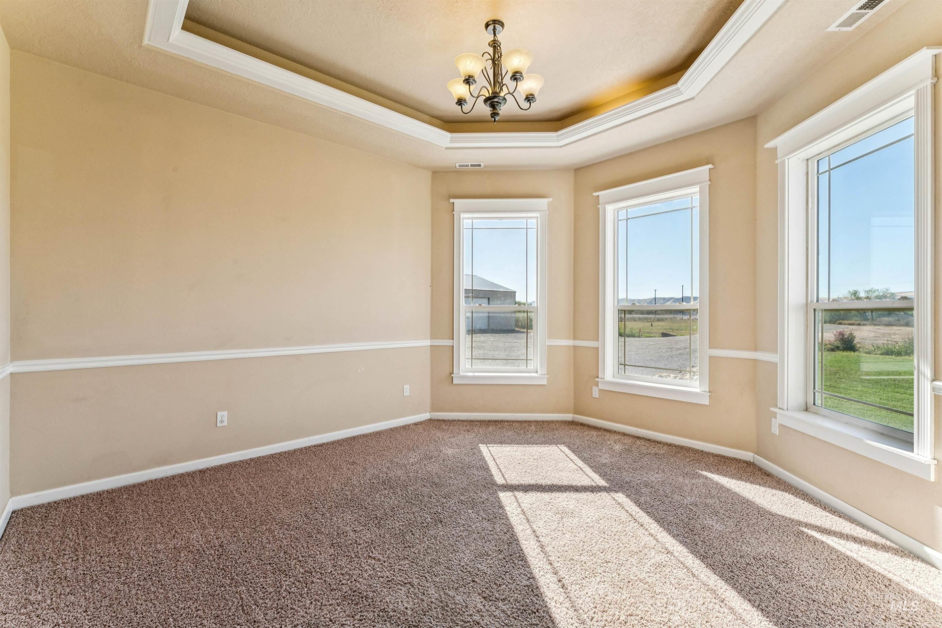 Carpeted spare room with a chandelier and a raised ceiling