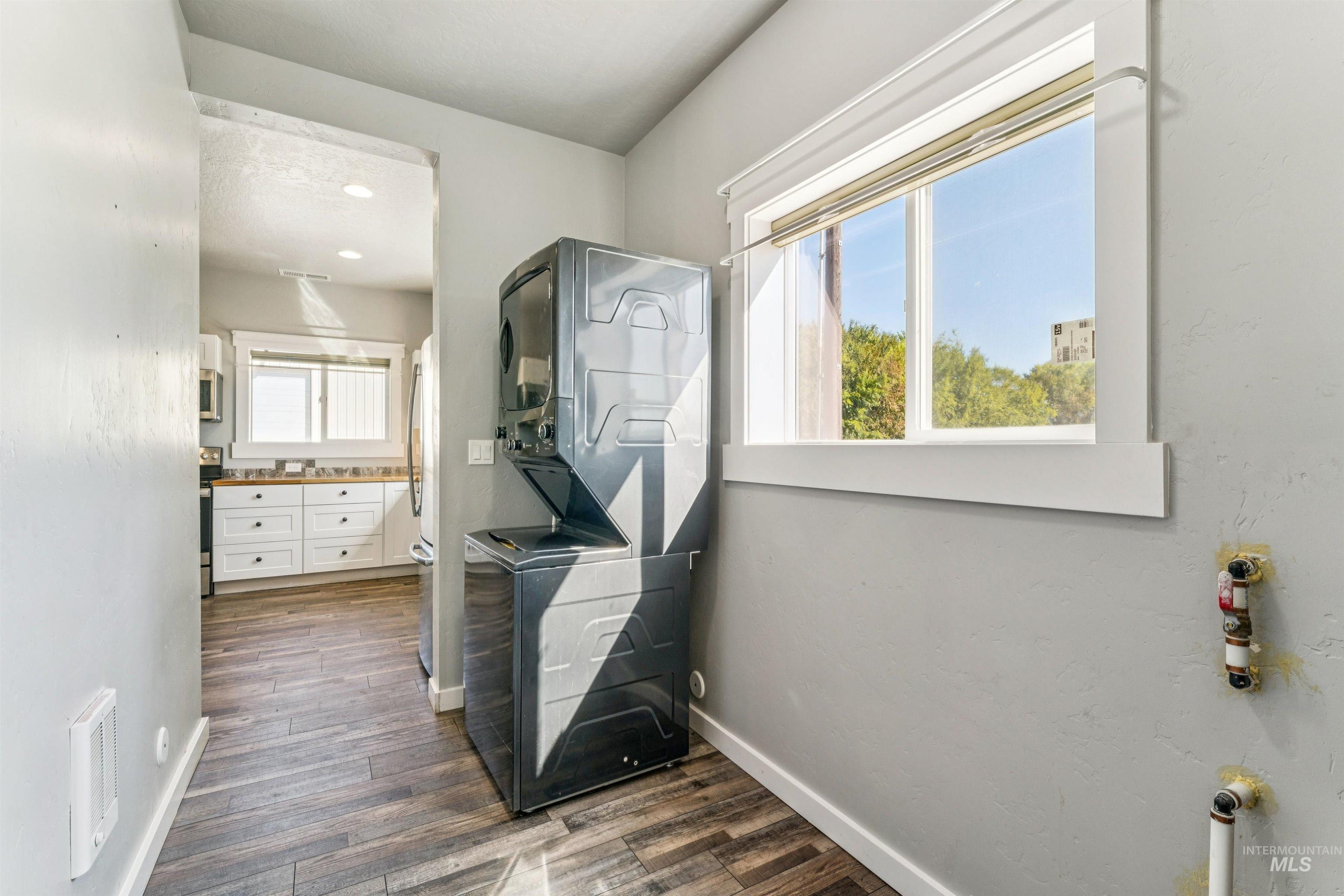 Hallway featuring stacked washer and clothes dryer, dark wood-style flooring, and recessed lighting