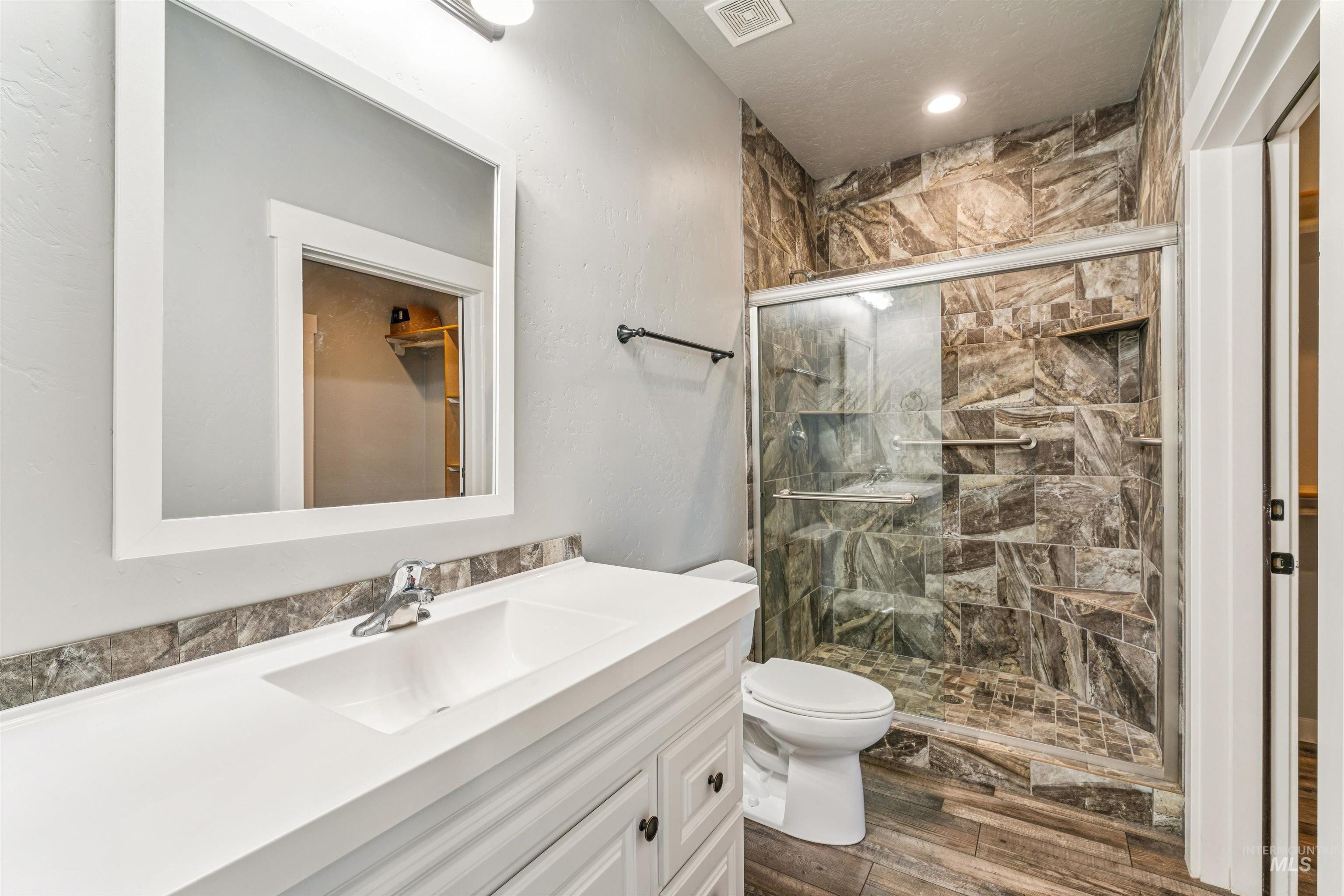 Full bathroom featuring a shower stall, vanity, dark wood-style floors, and recessed lighting