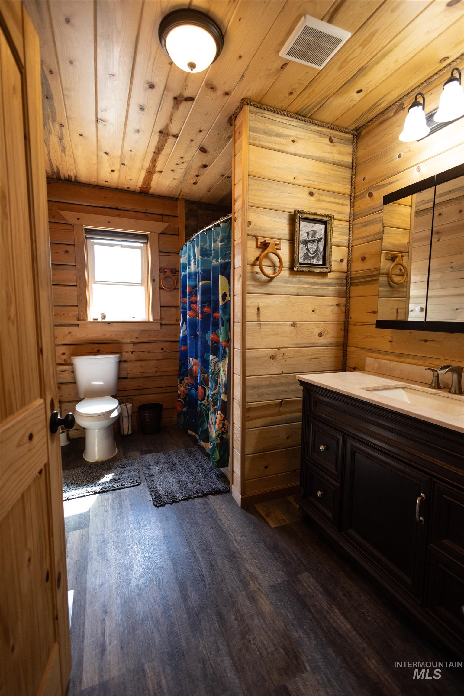 Full bathroom with dark wood-type flooring, vanity, wood walls, wooden ceiling, and a shower stall