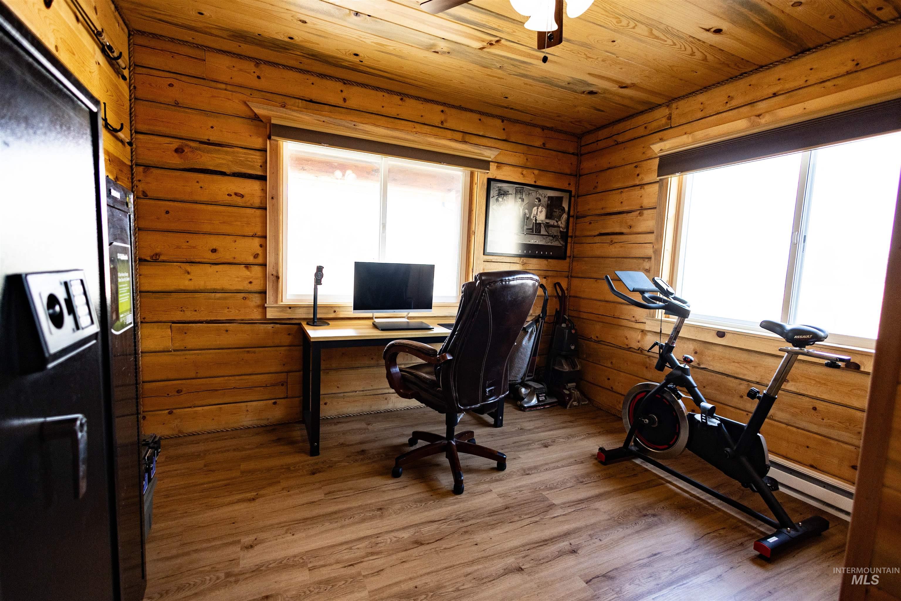 Home office featuring wood finished floors, wooden ceiling, healthy amount of natural light, ceiling fan, and a baseboard heating unit