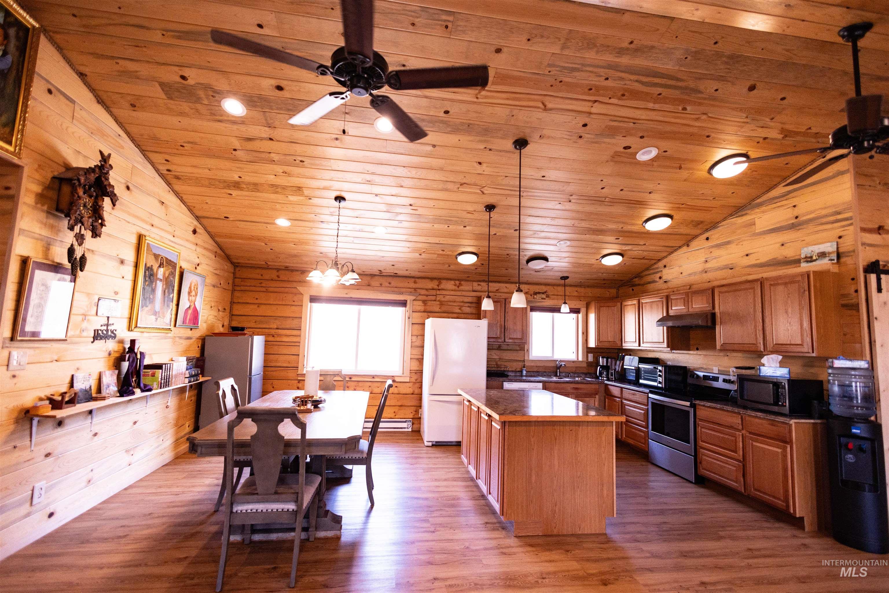Kitchen with dark countertops, decorative light fixtures, appliances with stainless steel finishes, brown cabinets, and dark wood finished floors