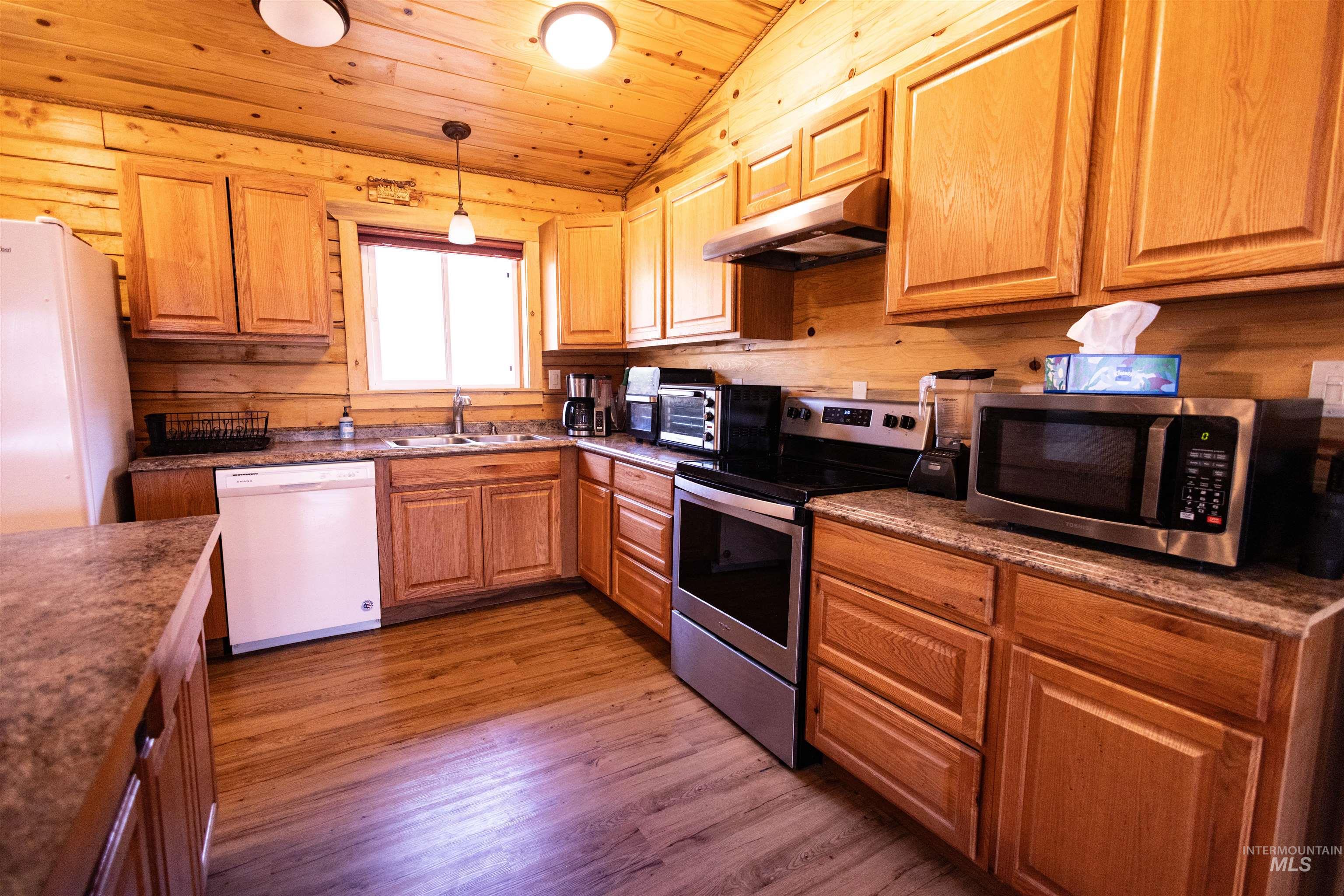 Kitchen with wood ceiling, stainless steel appliances, dark wood-style floors, vaulted ceiling, and under cabinet range hood