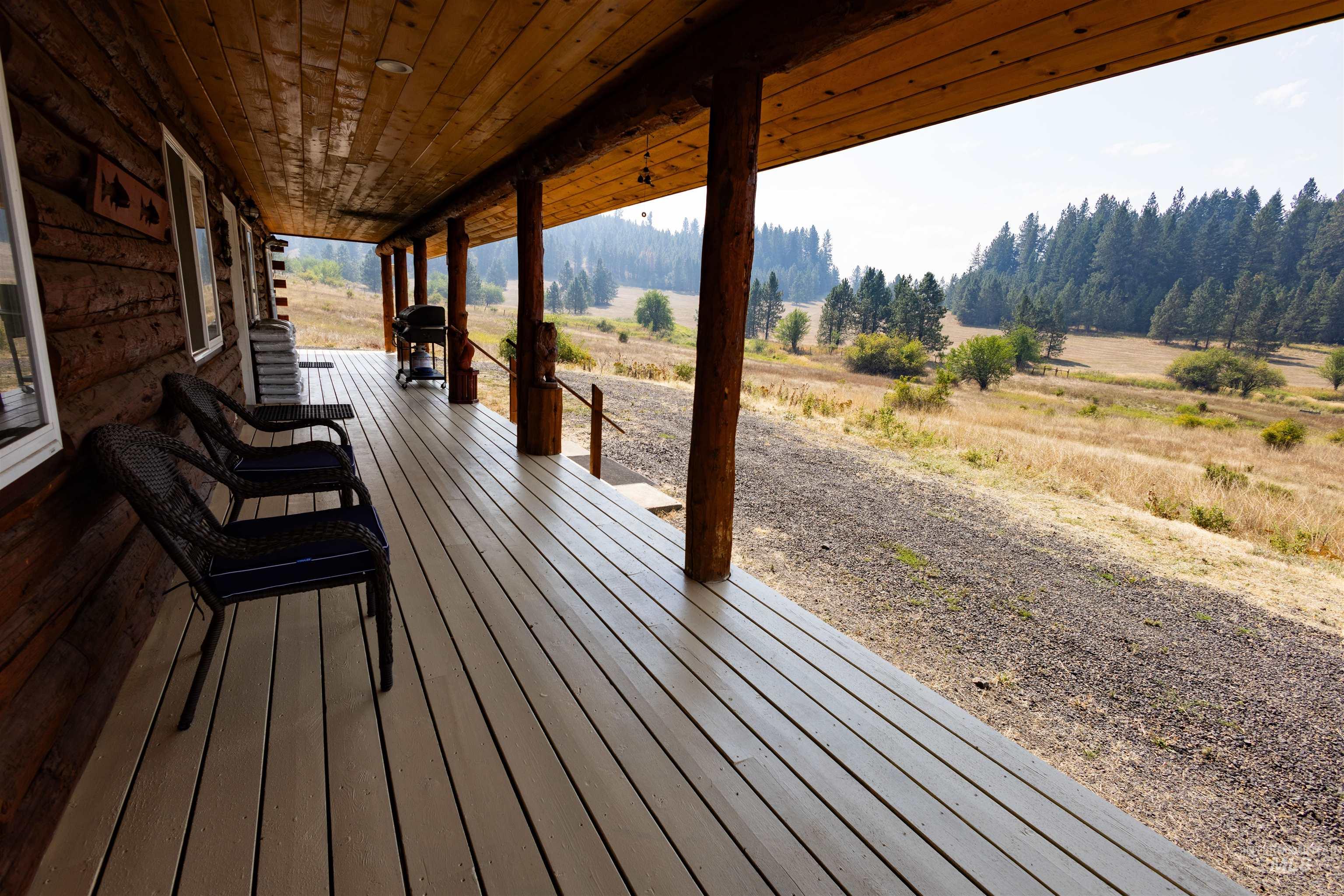Wooden porch with a view of countryside and area for grilling