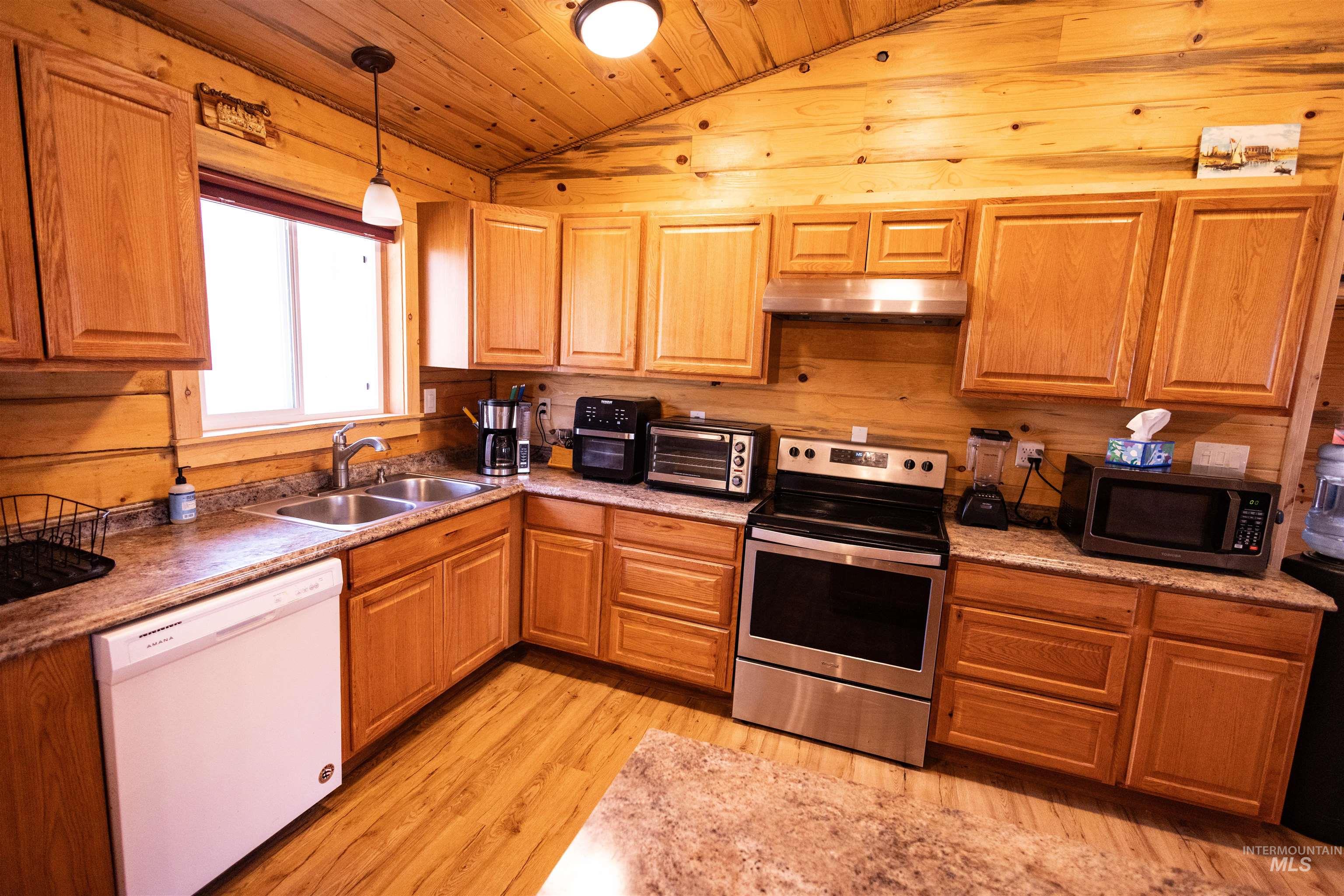 Kitchen with appliances with stainless steel finishes, wooden ceiling, lofted ceiling, hanging light fixtures, and light wood finished floors