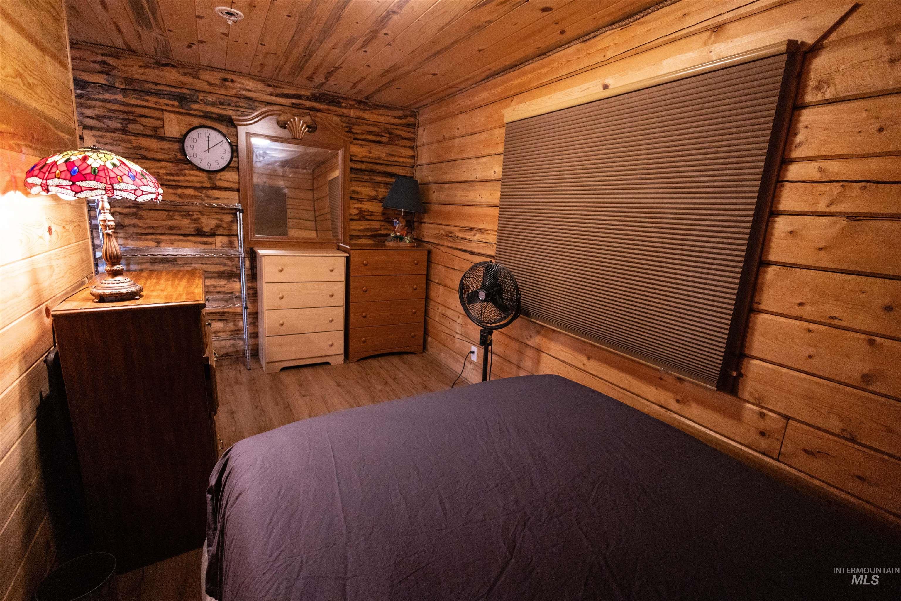 Bedroom featuring wood finished floors, wooden ceiling, and wood walls