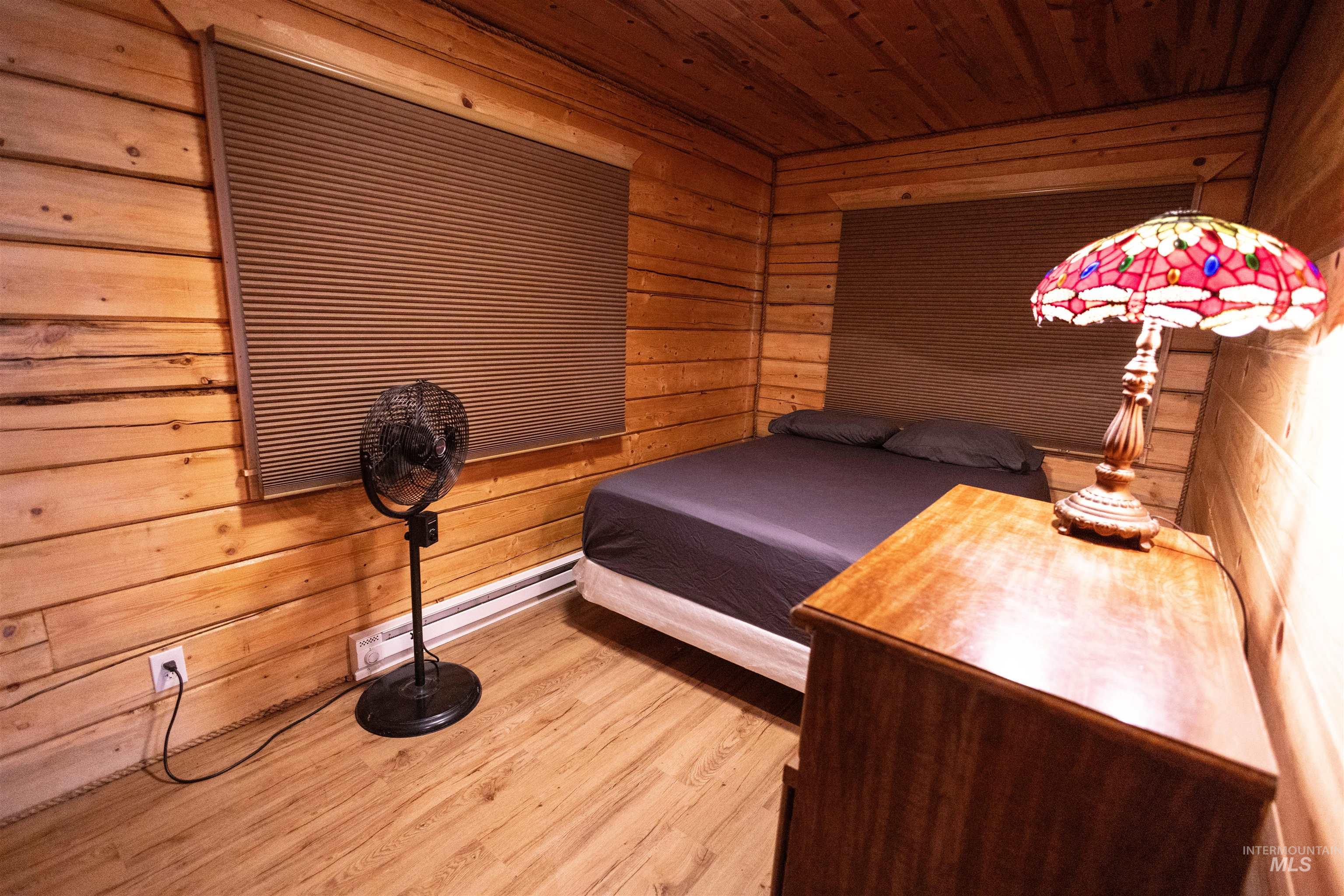 Bedroom with wooden walls, light wood-style flooring, and wooden ceiling