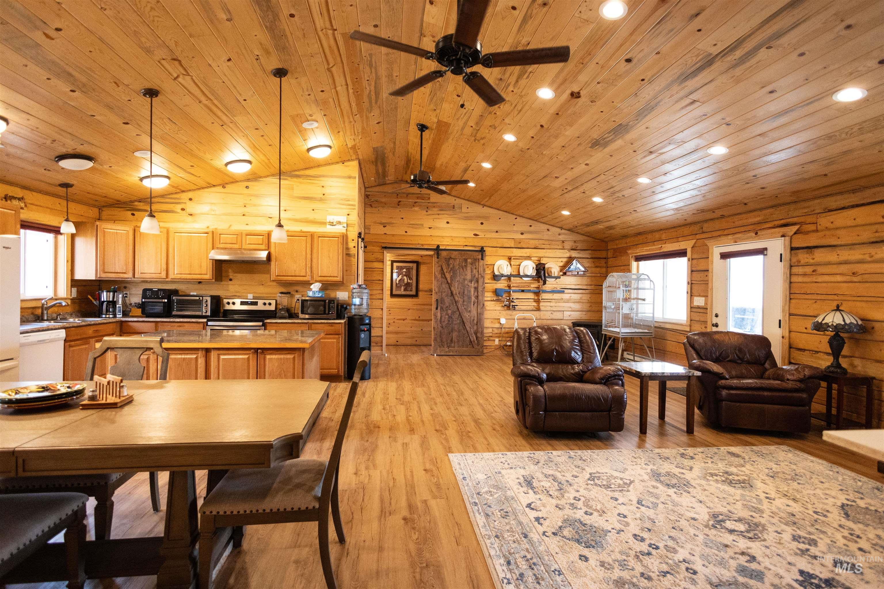 Dining room with light wood-type flooring, vaulted ceiling, a ceiling fan, wooden ceiling, and recessed lighting