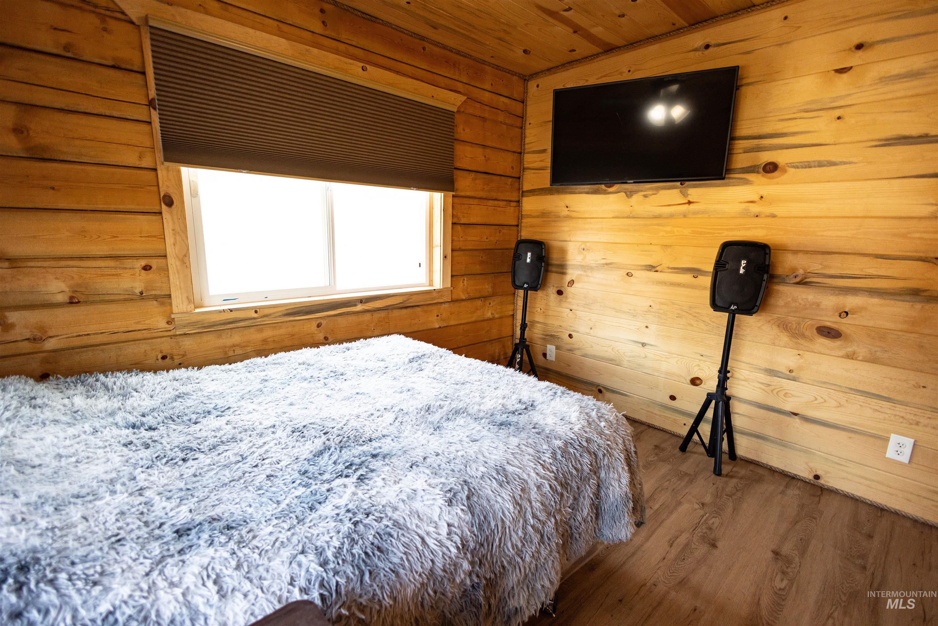 Bedroom with wood walls, wood finished floors, and wooden ceiling