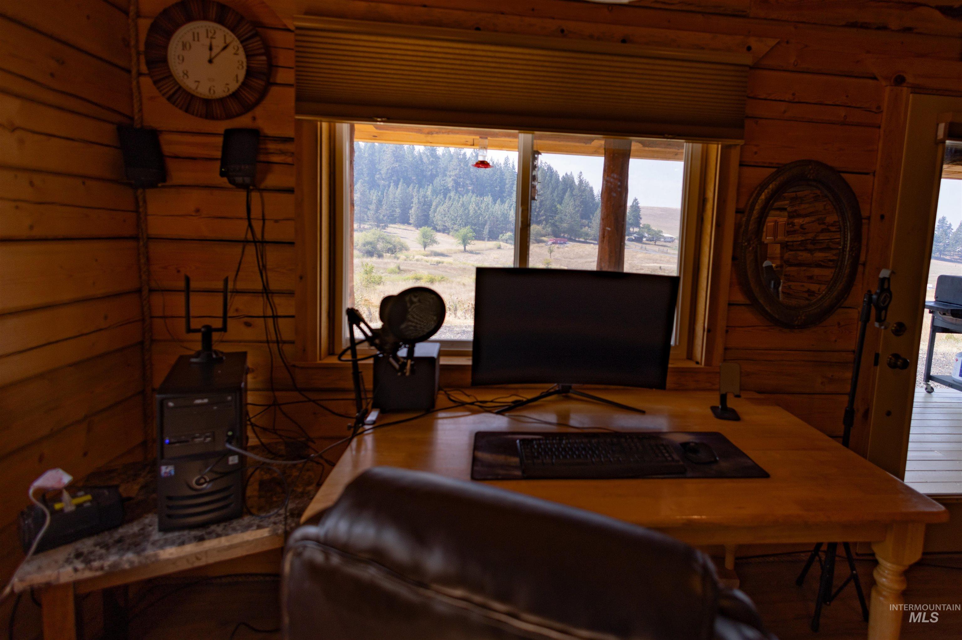Living area featuring wood walls, healthy amount of natural light, a desk, and wood finished floors