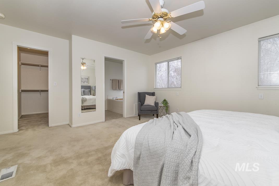 Carpeted bedroom with ensuite bath, a spacious closet, and ceiling fan
