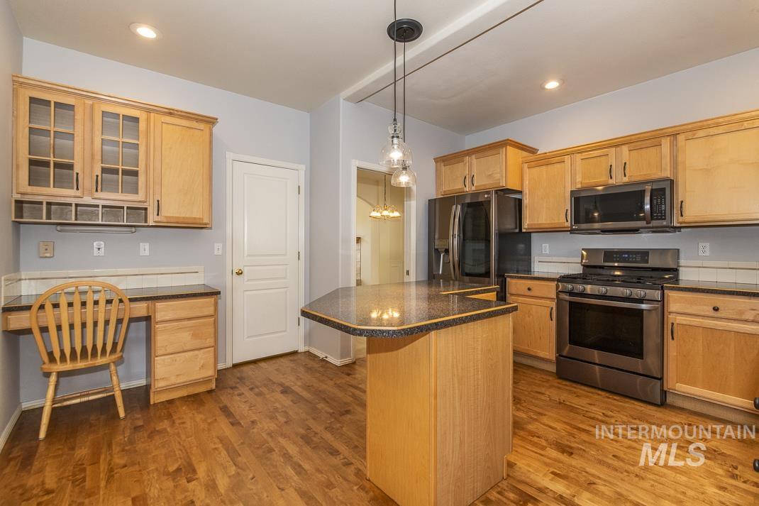 Kitchen featuring appliances with stainless steel finishes, glass insert cabinets, dark wood-style flooring, a kitchen island, and recessed lighting