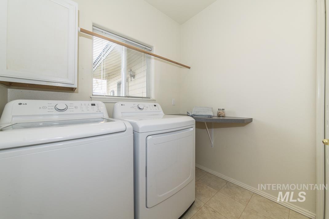 Laundry room featuring independent washer and dryer and light tile patterned flooring