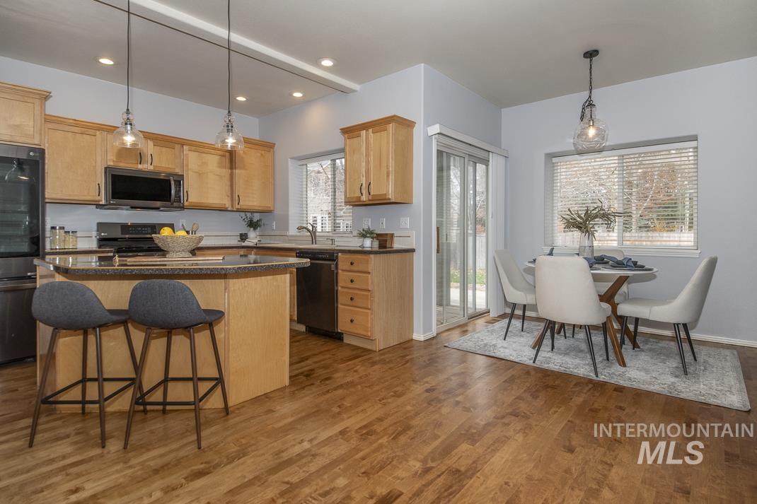 Kitchen with hanging light fixtures, a kitchen island, black appliances, a breakfast bar, and recessed lighting
