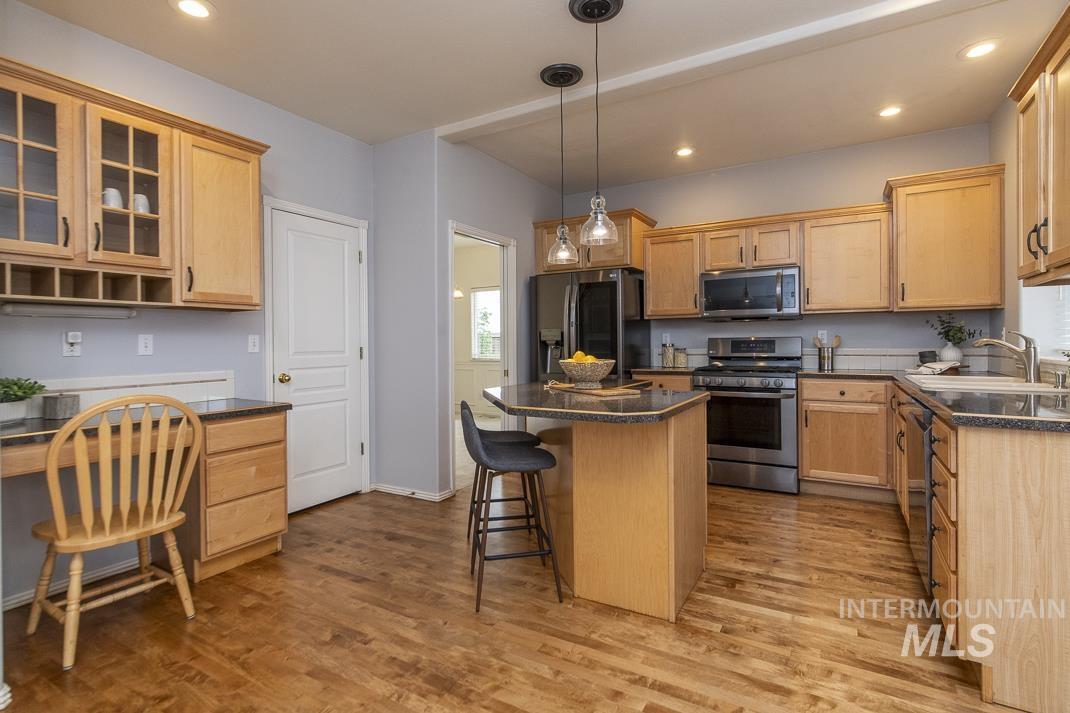 Kitchen featuring stainless steel appliances, recessed lighting, a kitchen breakfast bar, a kitchen island, and glass insert cabinets
