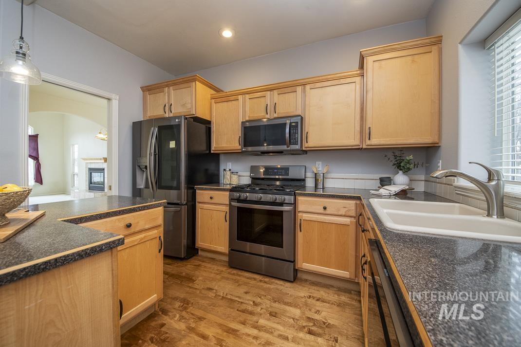 Kitchen featuring stainless steel appliances, light brown cabinets, pendant lighting, dark wood-style floors, and recessed lighting