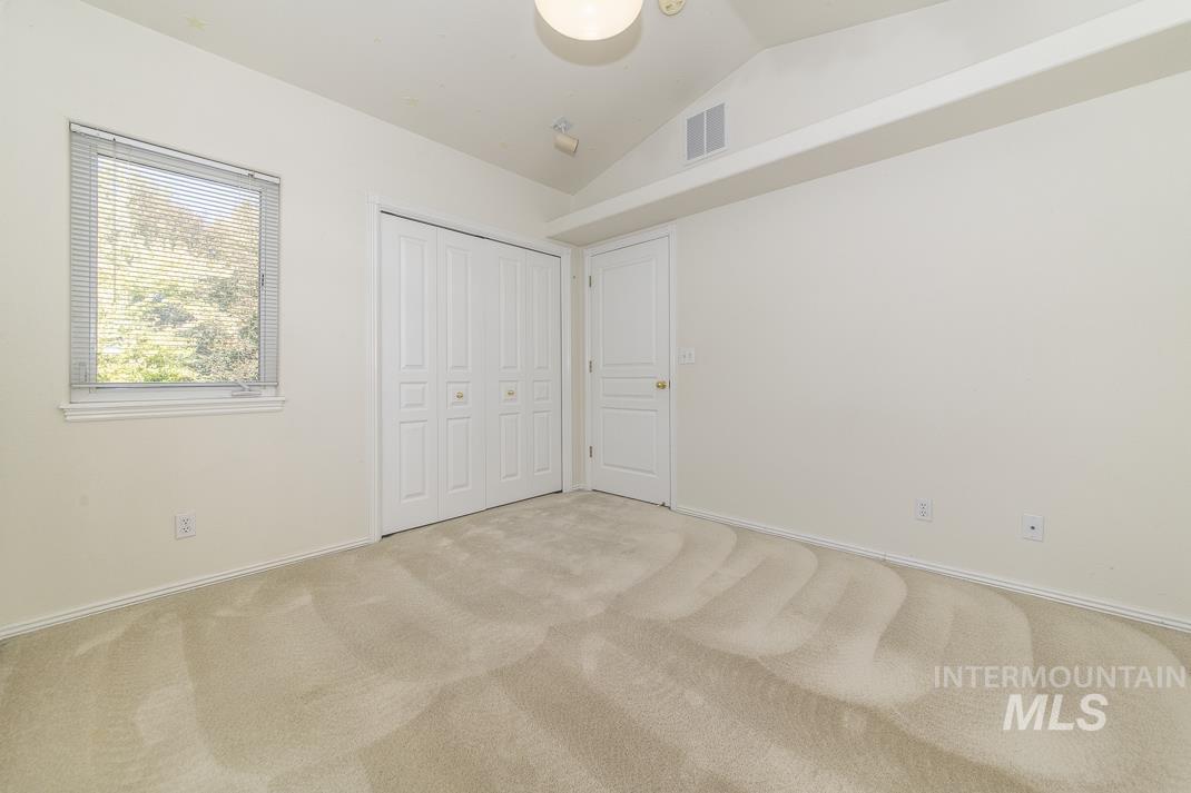 Unfurnished bedroom with vaulted ceiling, carpet, and a closet