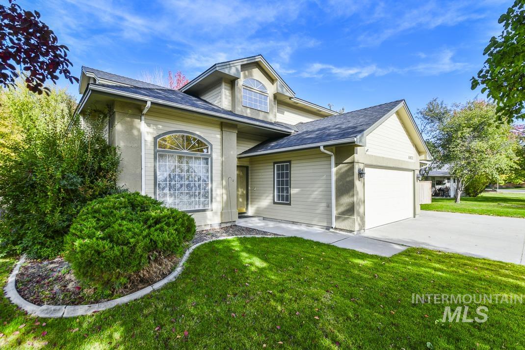 View of front of property featuring a garage, driveway, a front yard, and roof with shingles
