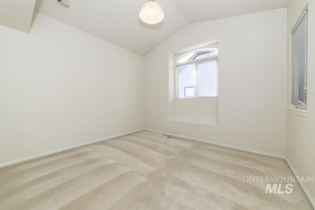 Empty room with carpet floors and lofted ceiling