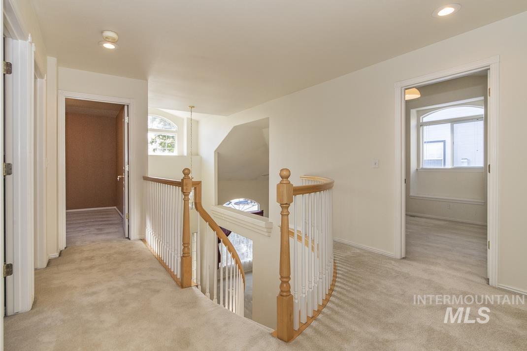 Hallway featuring an upstairs landing, light carpet, and recessed lighting