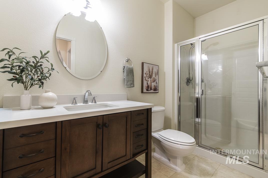 Full bathroom featuring vanity, a stall shower, and light tile patterned floors