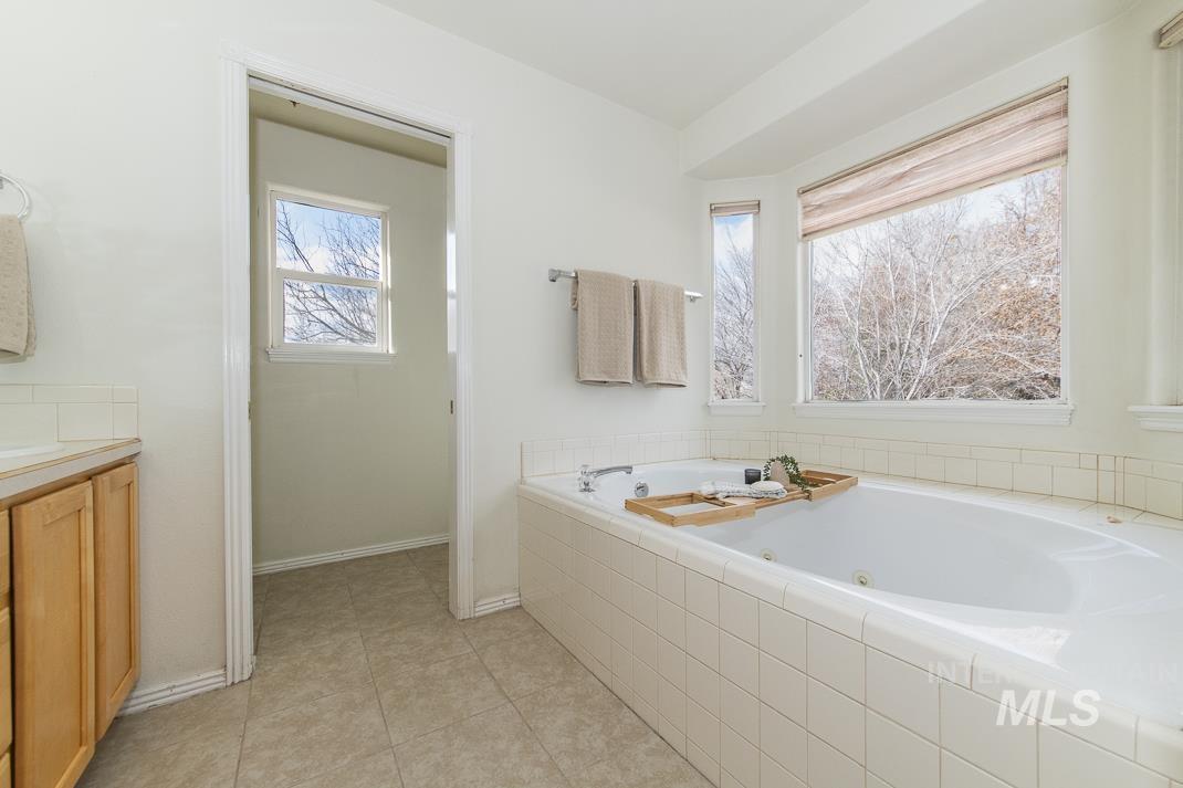 Bathroom with a tub with jets, vanity, and light tile patterned flooring