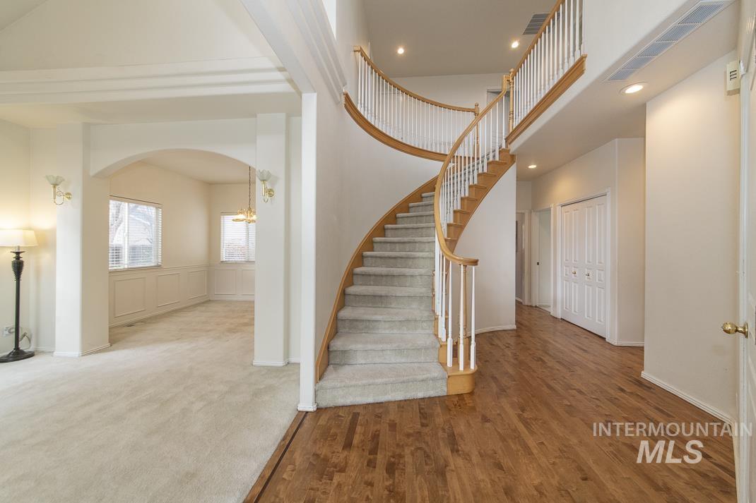 Stairway featuring recessed lighting, wood finished floors, a towering ceiling, arched walkways, and carpet flooring