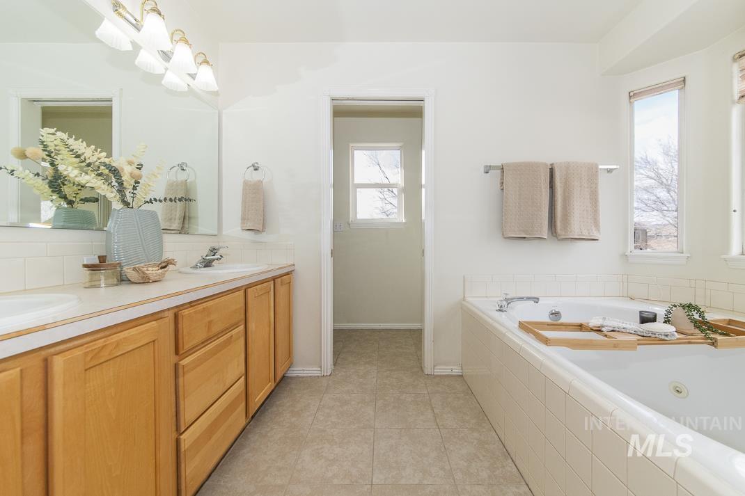 Bathroom with double vanity, a whirlpool tub, light tile patterned floors, and backsplash