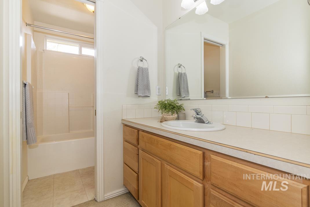 Bathroom featuring vanity, shower / bath combination, tasteful backsplash, and light tile patterned floors