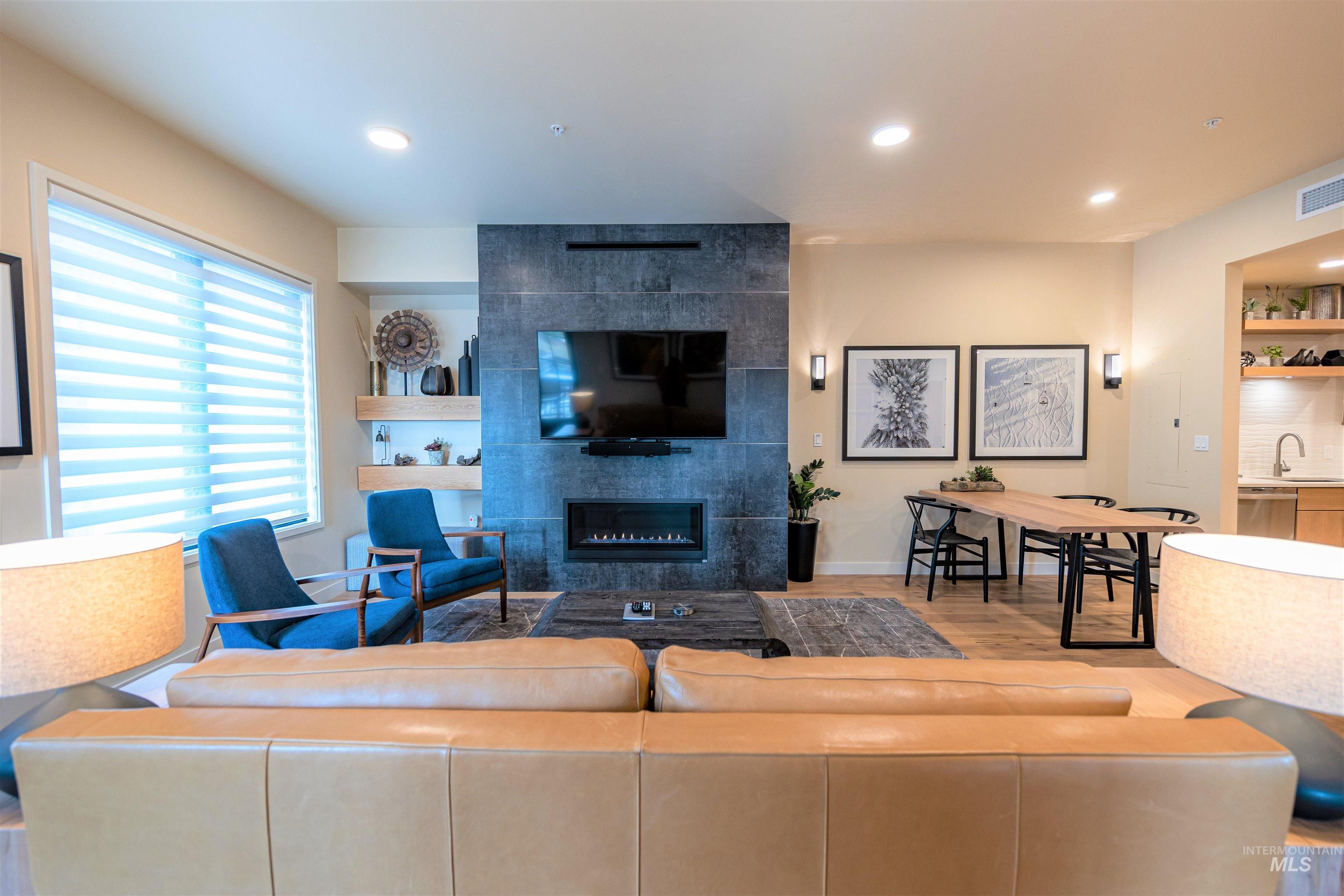 Living room with a fireplace, wood finished floors, and recessed lighting