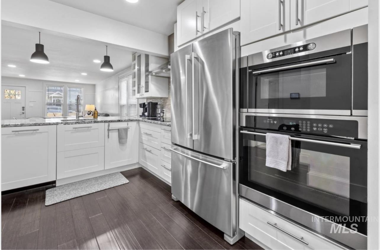 Kitchen with appliances with stainless steel finishes, white cabinetry, light stone counters, pendant lighting, and recessed lighting