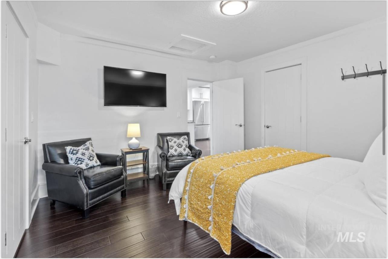 Bedroom with attic access, dark wood-style floors, and stainless steel fridge
