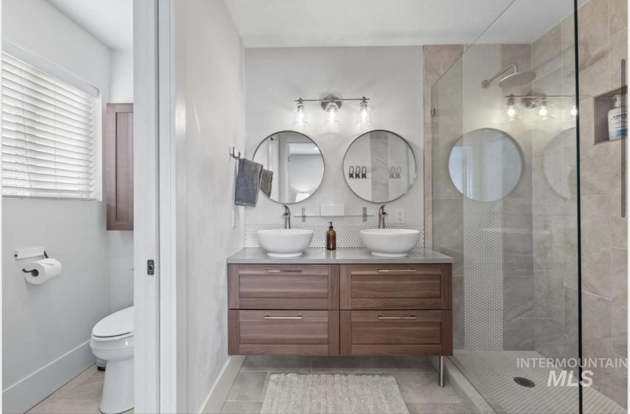 Full bathroom with double vanity, a walk in shower, and light tile patterned floors