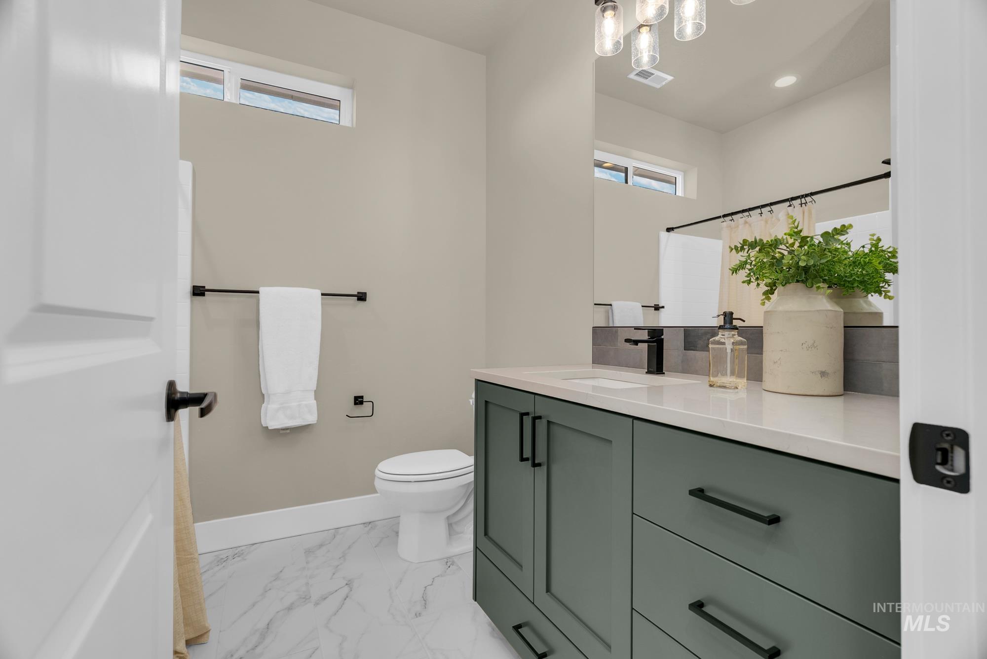 Bathroom featuring vanity, a shower with shower curtain, light marble finish flooring, and recessed lighting