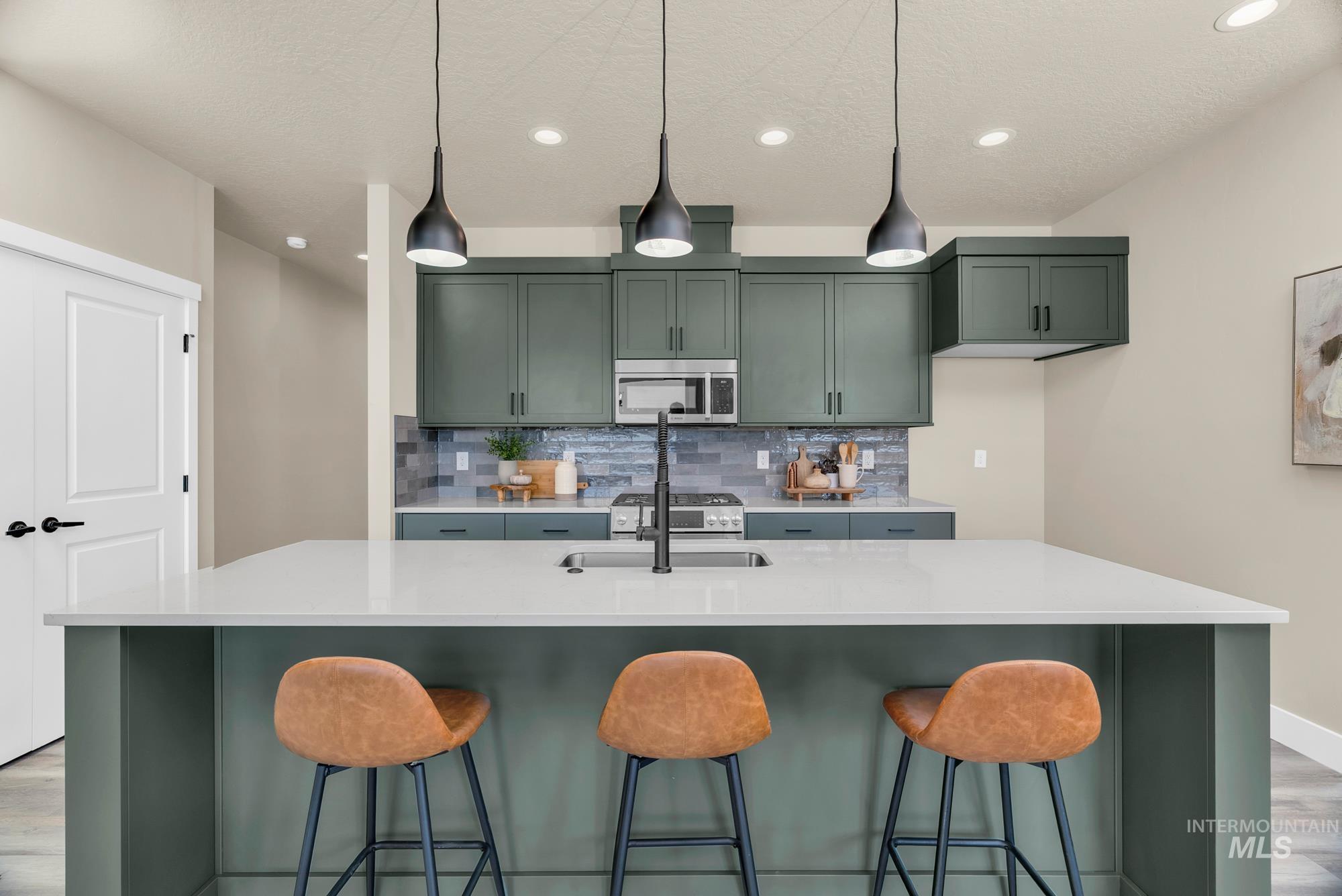 Kitchen with light wood-style floors, green cabinets, backsplash, a kitchen island with sink, and recessed lighting