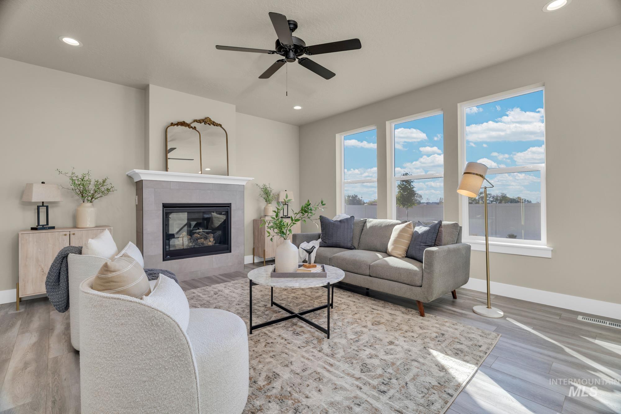 Living area with a tiled fireplace, recessed lighting, wood finished floors, and ceiling fan