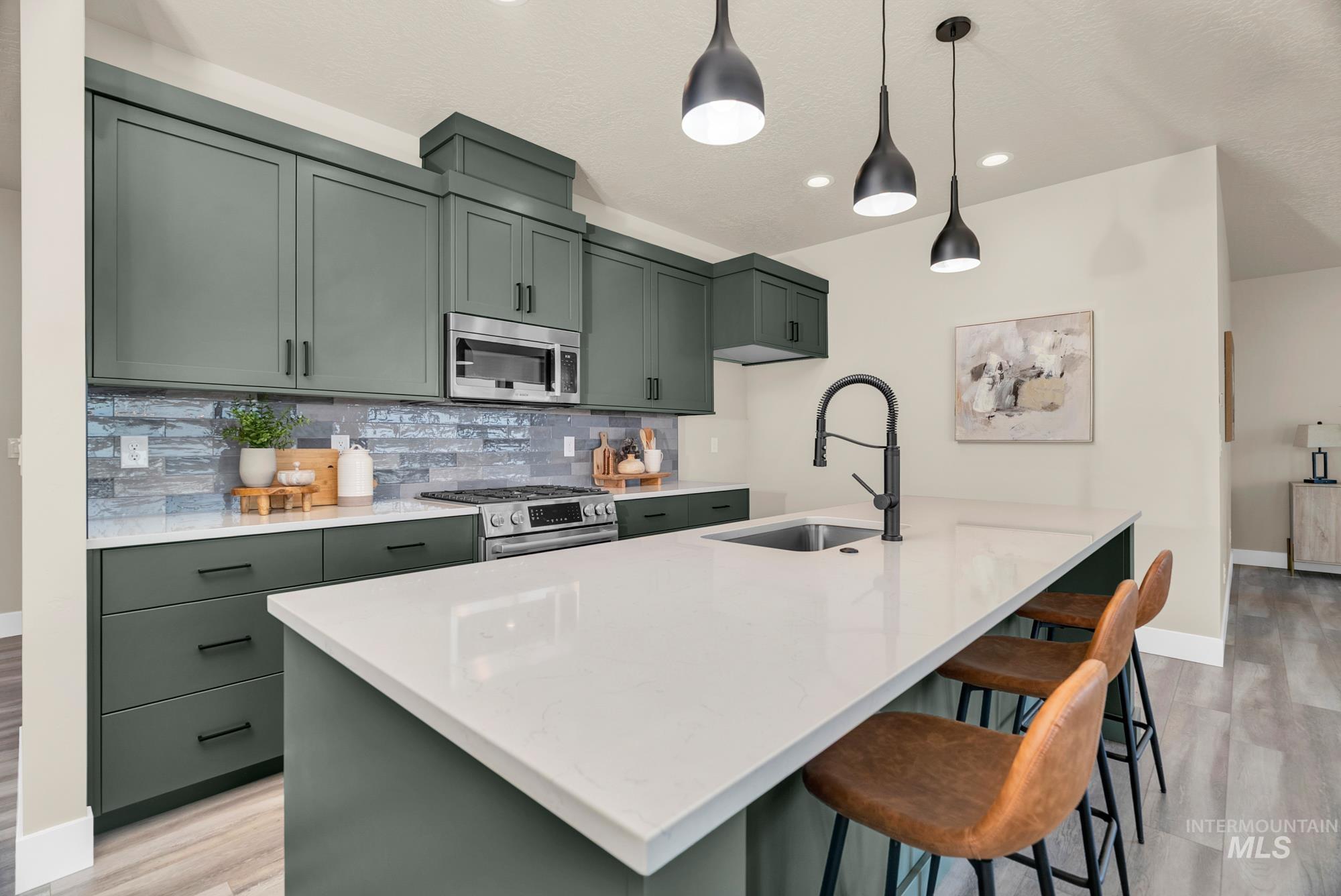 Kitchen with green cabinetry, backsplash, light wood-style floors, light stone countertops, and recessed lighting