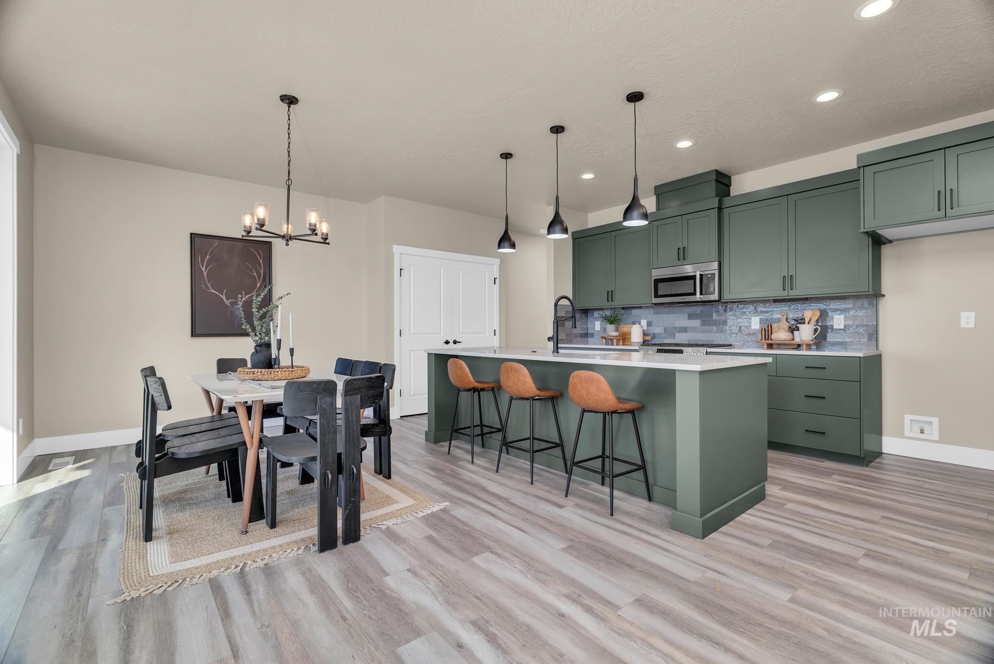 Kitchen with green cabinets, decorative backsplash, decorative light fixtures, a breakfast bar, and recessed lighting