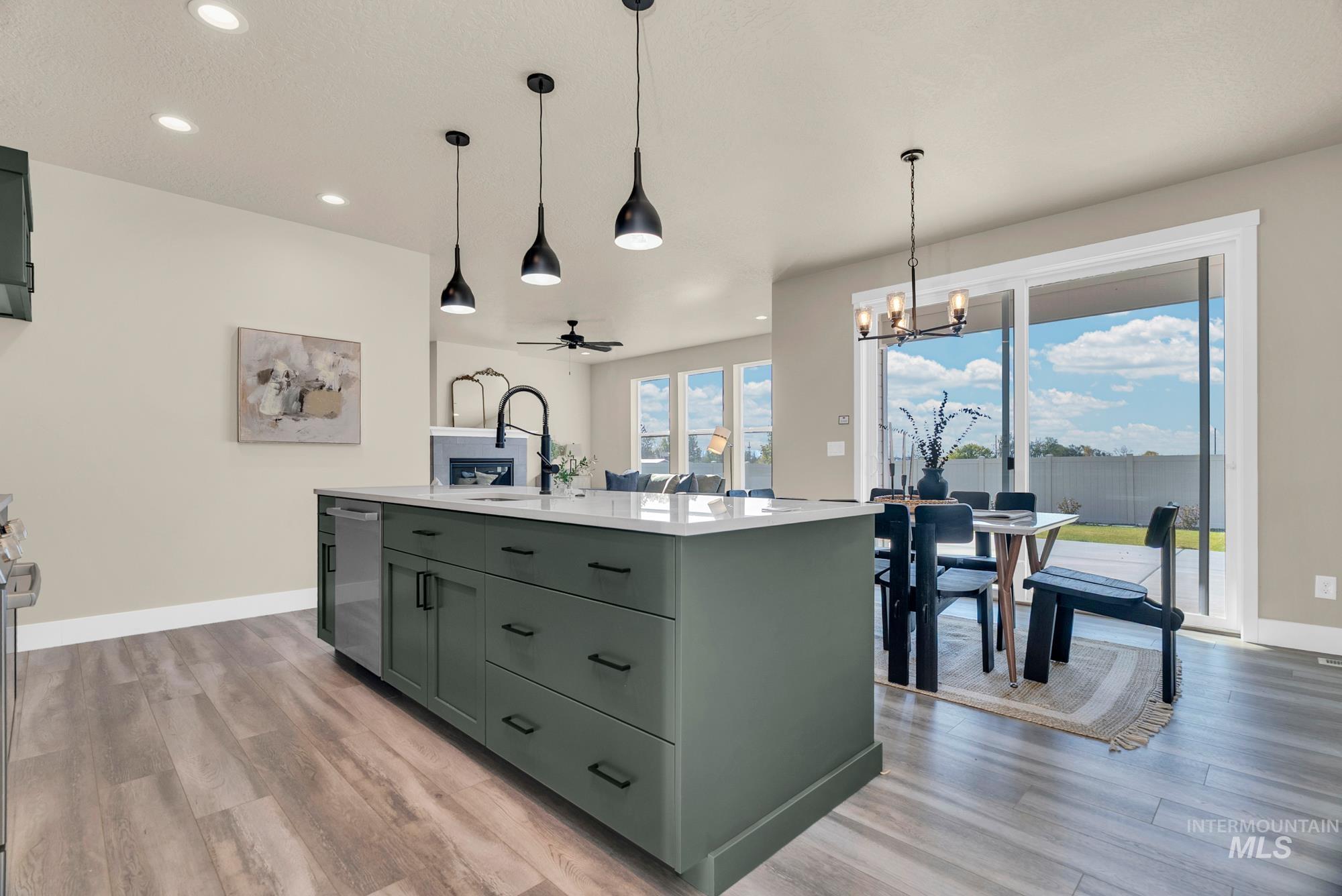 Kitchen featuring green cabinetry, a kitchen island with sink, a chandelier, decorative light fixtures, and recessed lighting