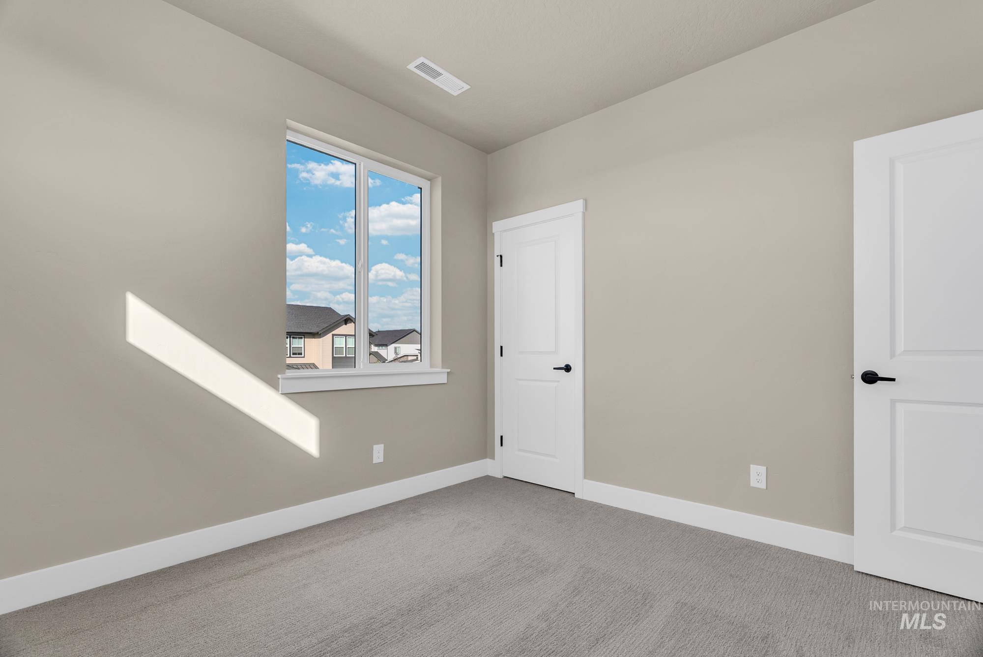 Spare room featuring carpet flooring and baseboards