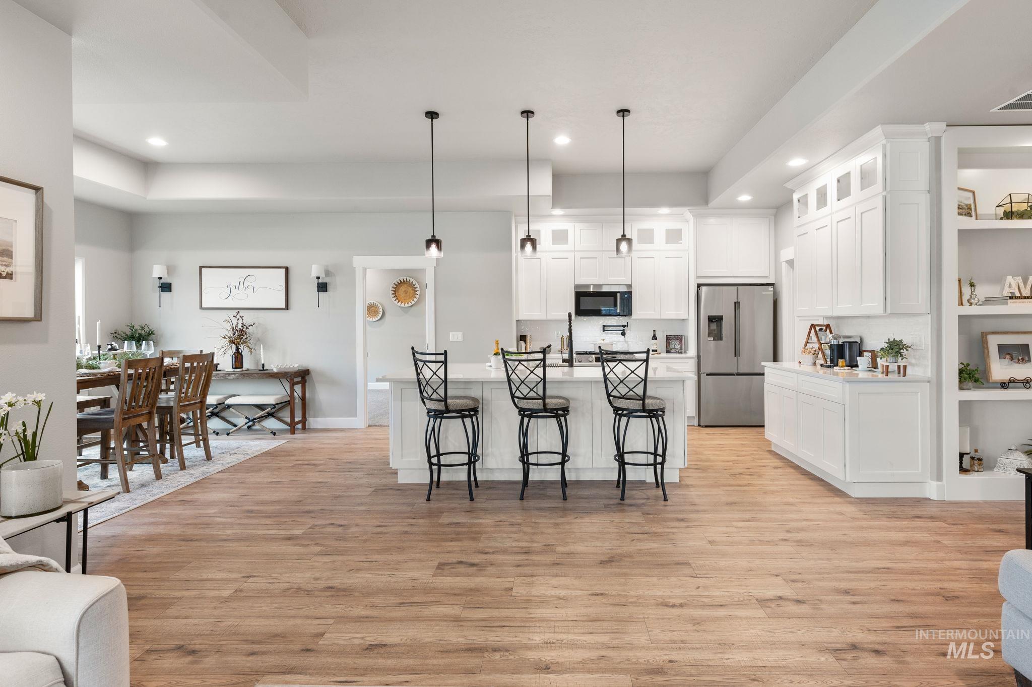 Kitchen with white cabinetry, recessed lighting, light wood finished floors, stainless steel appliances, and a kitchen bar