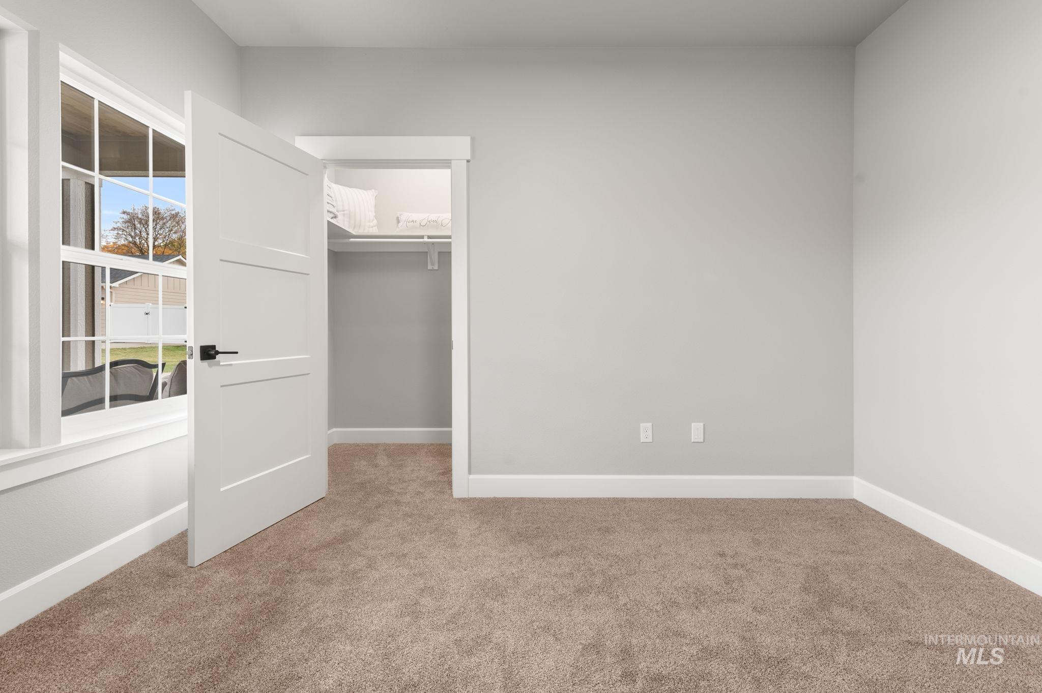 Unfurnished bedroom featuring a walk in closet and light carpet