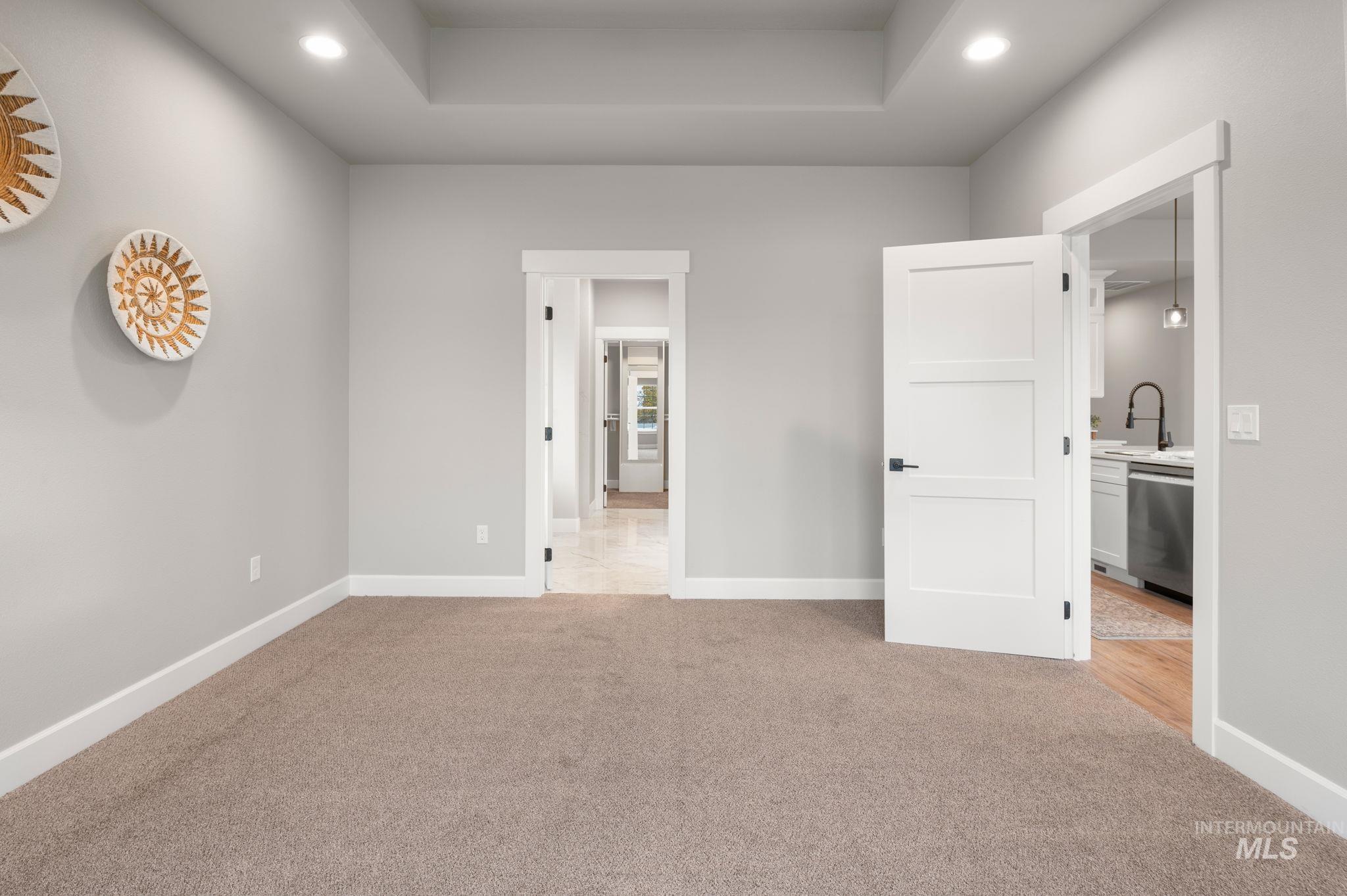 Unfurnished bedroom featuring recessed lighting, light carpet, a tray ceiling, and connected bathroom
