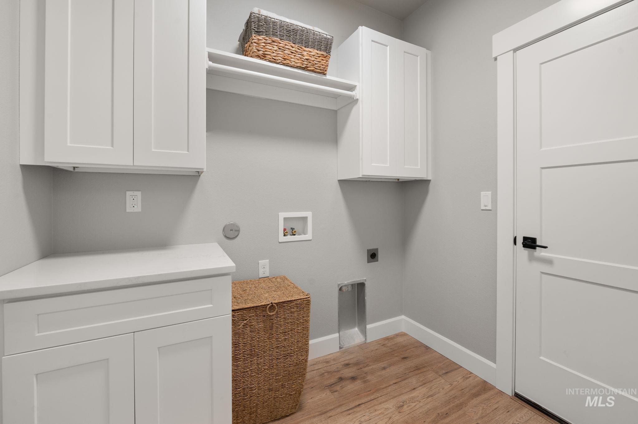 Laundry room featuring light wood-style floors, washer hookup, cabinet space, and hookup for an electric dryer