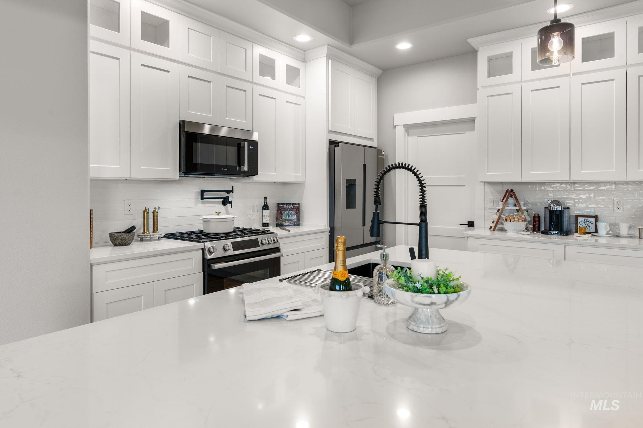 Kitchen featuring tasteful backsplash, glass insert cabinets, white cabinets, appliances with stainless steel finishes, and recessed lighting