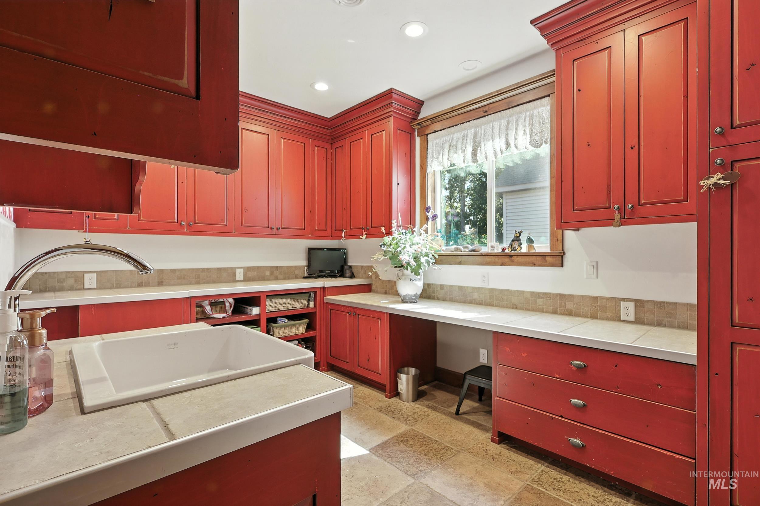 Kitchen with dark brown cabinets, built in study area, recessed lighting, and tile counters